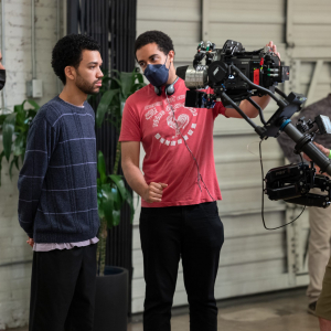 (L to R) Director of photography Doug Emmett, actor Justice Smith and writer/director Kobi Libii on the set of THE AMERICAN SOCIETY OF MAGICAL NEGROES, a Focus Features release. Credit: Tobin Yelland / Focus Features